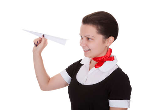 Beautiful flight attendant holding an origami paper airplane in her hand conceptual of airline flight and travel isolated on whiteの写真素材