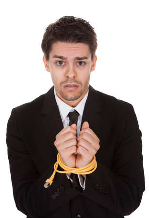 Businessman with hands tied in network cable. Isolated on whiteの写真素材