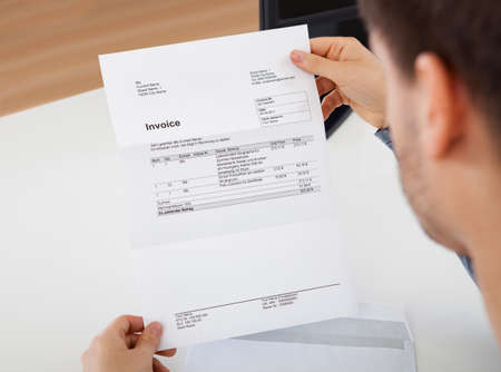 Overhead view of young man reading a invoice documentの写真素材