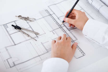 Closeup cropped image of a young male architect working on blueprints spread out on a table