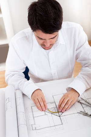 Closeup cropped image of a young male architect working on blueprints spread out on a table