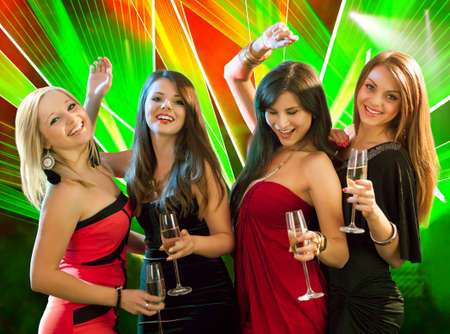 Group of four stylish women standing in a row toasting with flutes of champagne