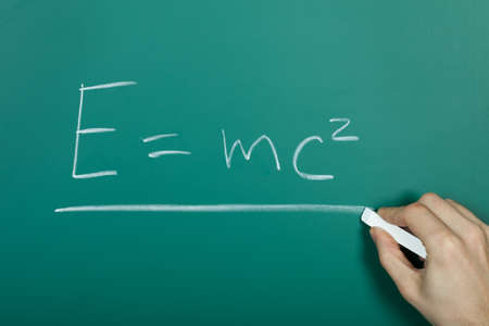 Hand writing relativity formula on green blackboardの写真素材