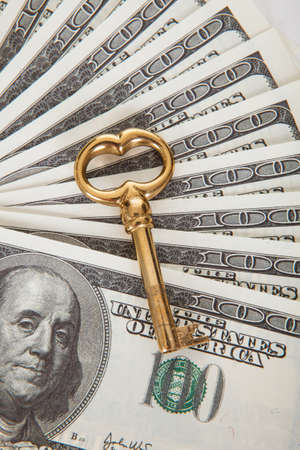Golden key on top of 100 dollars billsの写真素材