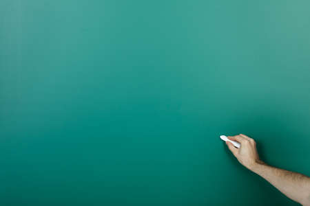 Hand holding chalk writing on green blackboardの写真素材
