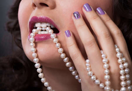 Portrait Of Beautiful Young Woman Holding Pearl Necklaceの写真素材