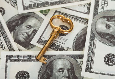 Golden key on top of 100 dollars billsの写真素材