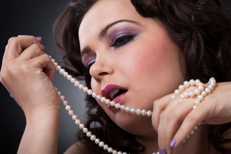 Portrait Of Beautiful Young Woman Holding Pearl Necklaceの写真素材