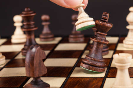 Close-up Of Hand Playing Chess And Falling Kingの写真素材