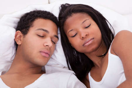 Portrait Of Young Couple Sleeping On Bedの写真素材