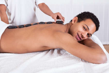 Close-up Of Woman Hand Placing Lastone On Man Backの写真素材