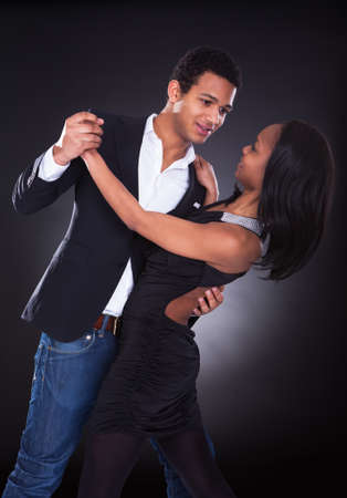 Portrait Of Young African Couple Dancing Over Grey Backgroundの写真素材