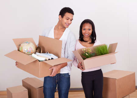Portrait Of Young Couple Carrying Boxes In House