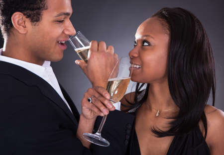 Portrait Of African Couple Enjoying Champagne Drink Over Grey Backgroundの写真素材