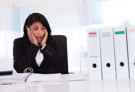 Shocked Businesswoman Looking At Folder In Officeの写真素材