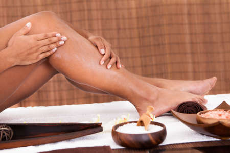 Close-up Of Young Woman's Feet Applying Oil For Massageの写真素材
