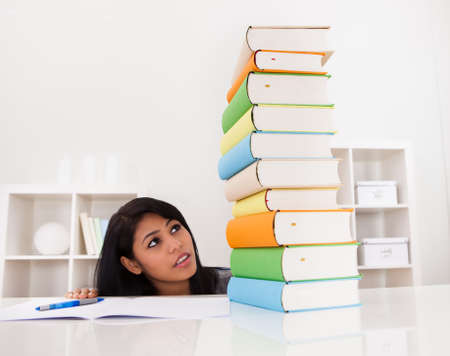 Shocked Woman Looking At Stack Of Books Indoorの写真素材
