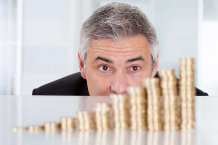 Happy Mature Businessman With Stack Of Coinsの写真素材