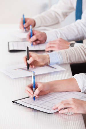 Business People Sitting In A Row And Writing Notes In Officeの写真素材