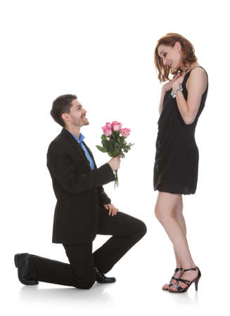 Young Man Offer Flower To Beautiful Woman Over White Backgroundの写真素材
