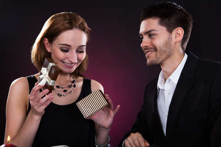 Portrait of happy couple holding gift on colored background