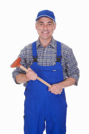 Portrait Of Male Plumber Holding Plunger Over White Backgroundの写真素材