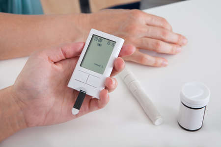 Close-up Of Hand Holding Sugar Level Checking Machine