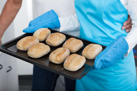 Man Looking At Woman Taking Baking Tray Out From Oven