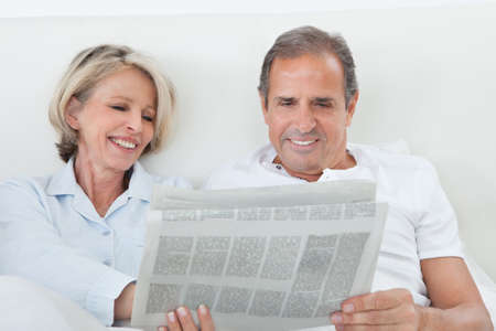 Portrait Of Mature Couple Reading Newspaper Together At Homeの写真素材