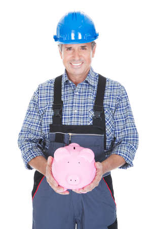 Portrait Of A Worker Holding Piggybank Over White Backgroundの写真素材