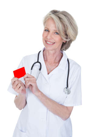 Mature Female Doctor Holding Visiting Card Over White Backgroundの写真素材
