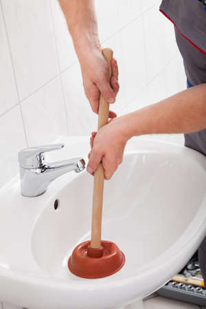 Portrait of male plumber pressing plunger in sinkの写真素材