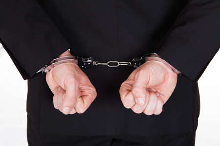 Rear view of arrested businessman with handcuffs