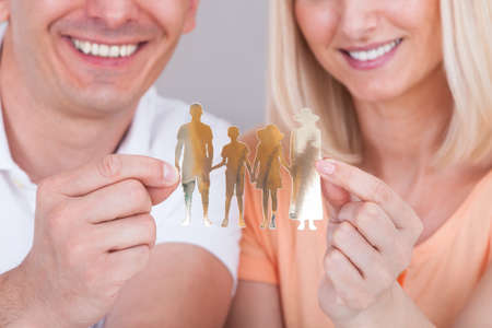 Portrait of happy couple holding family figure cut-outの写真素材