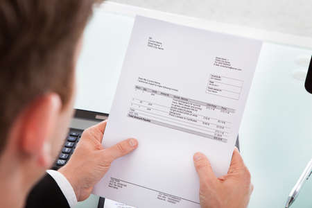 Portrait of a business man looking at invoice paper