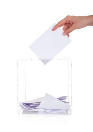 Closeup Of Hand Inserting Ballot In Box Over White Background