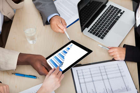 Multi Ethnic Business Colleagues Discussing Graph On Digital Tablet