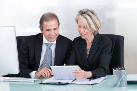 Happy Mature Businessman And Businesswoman Looking At Computerの写真素材
