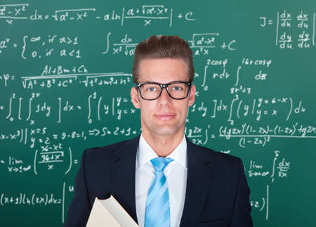 Young Male Lecturer Standing In Front Of Chalkboard