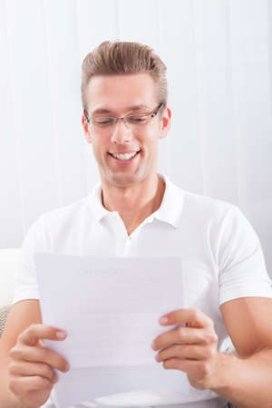 Happy Young Man Reading Paper Holding In Hands