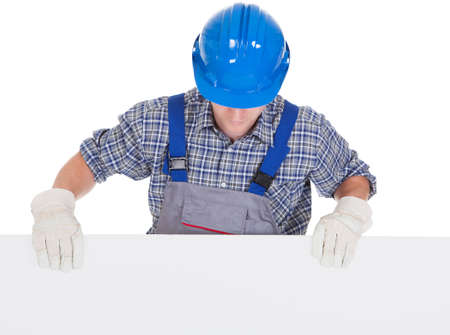 Worker wearing hardhat and holding blank placard isolated on white background