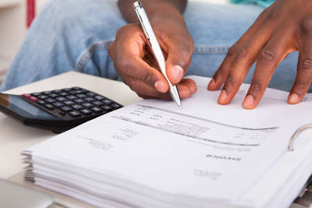 African Young Man Calculating His Finance Expenses At Home