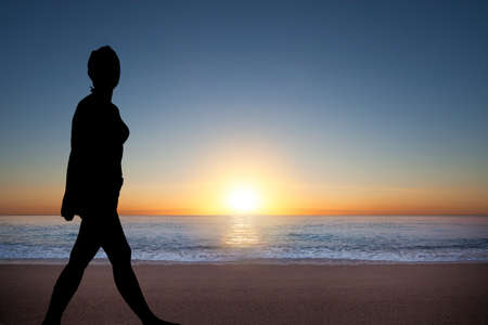 Silhouette of happy woman during sunrise at the seaの写真素材