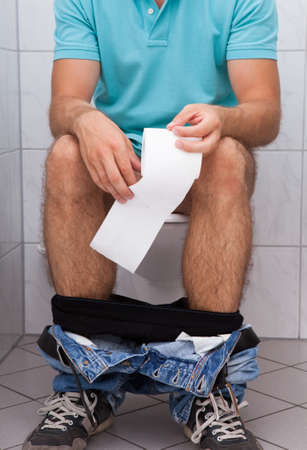 Close-up of a man in toilet holding tissue