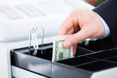 Close-up Of Hand With Dollar Notes Over Containerの写真素材