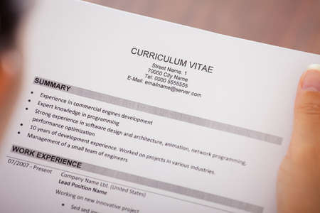 Close-up Of Young Businesswoman Reading Curriculum Vitae At Desk