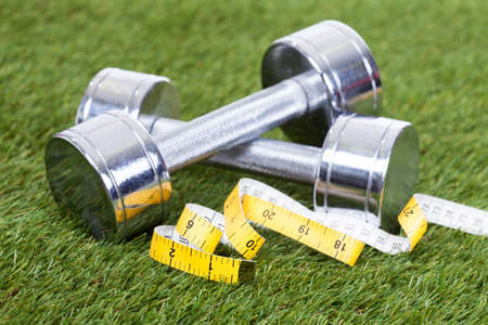 Dumbbells With Measuring Tape On Green Pitch