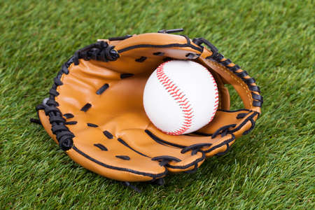 Leather Glove With Baseball Ball On Green Pitchの写真素材