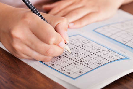Close-up Of Woman Hand Solving Sudoku With Penの写真素材