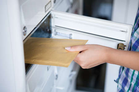 Close-up of woman's hand pulling envelop from mailboxの写真素材